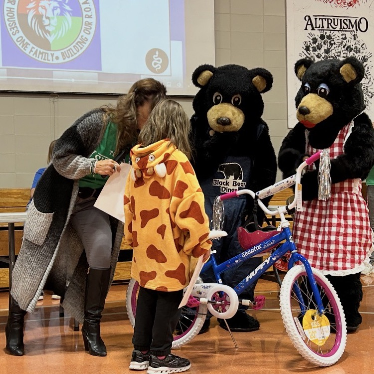 student posing with her new bike from Black Bear Diner - principal and people in bear costumes giving student the bike