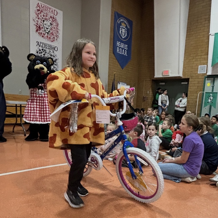 student posing with her new bike from Black Bear Diner - principal and people in bear costumes giving student the bike