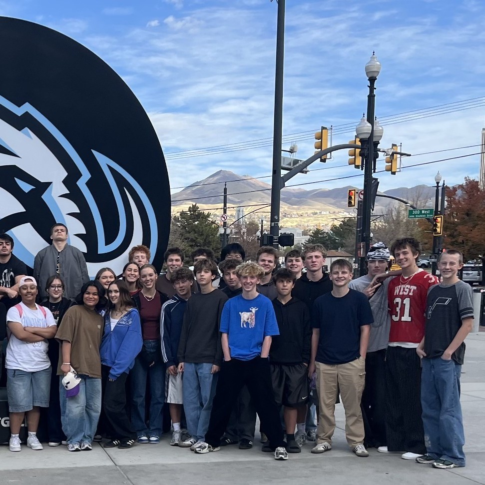 Plants are students standing in front of the mammoth sign at the delta center for the utah, jazz marketing event