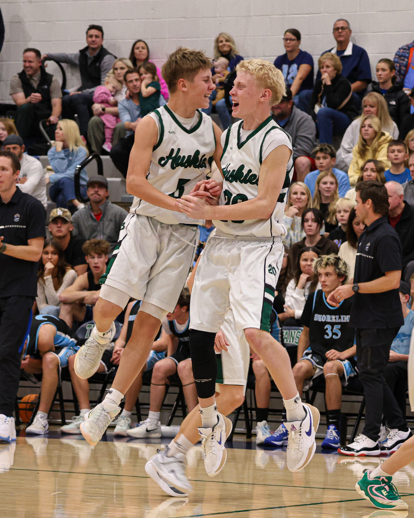 Two Farmington Junior High players jump together mid-air in celebration at the Davis School District Boys Basketball Championship Game. 