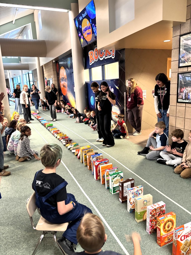 students sitting in the hallway watching ceral boxes tumble like dominos