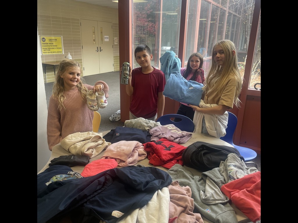 A photo of kids holding up clothes from the lost and found.