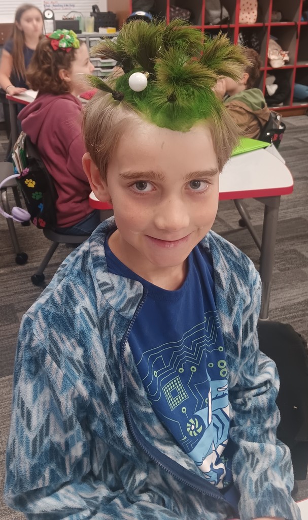 Student with hair dyed green in multiple ponytails with an ornament attached. 