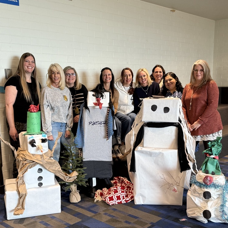 a group of women standing together in front of some cardboard wrapped snowmen