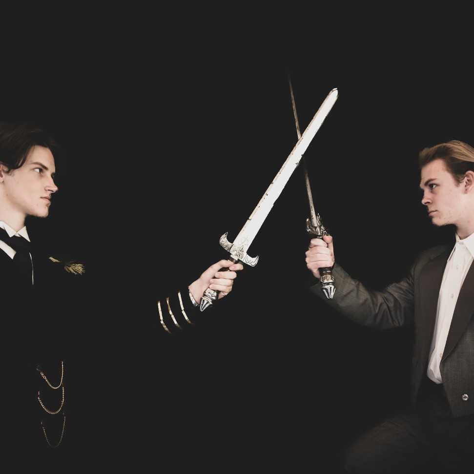 two male students acting in Les Mis facing off with swords