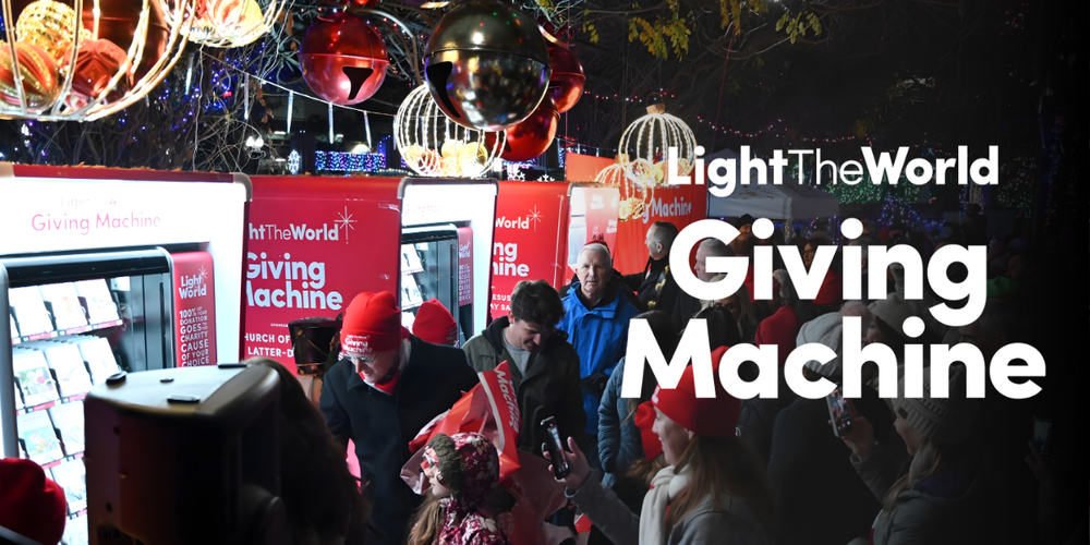 An image that says "Light The World Giving Machine" in big white letters. Behind the letters is an image of several Giving Machines, with people gathered around them.