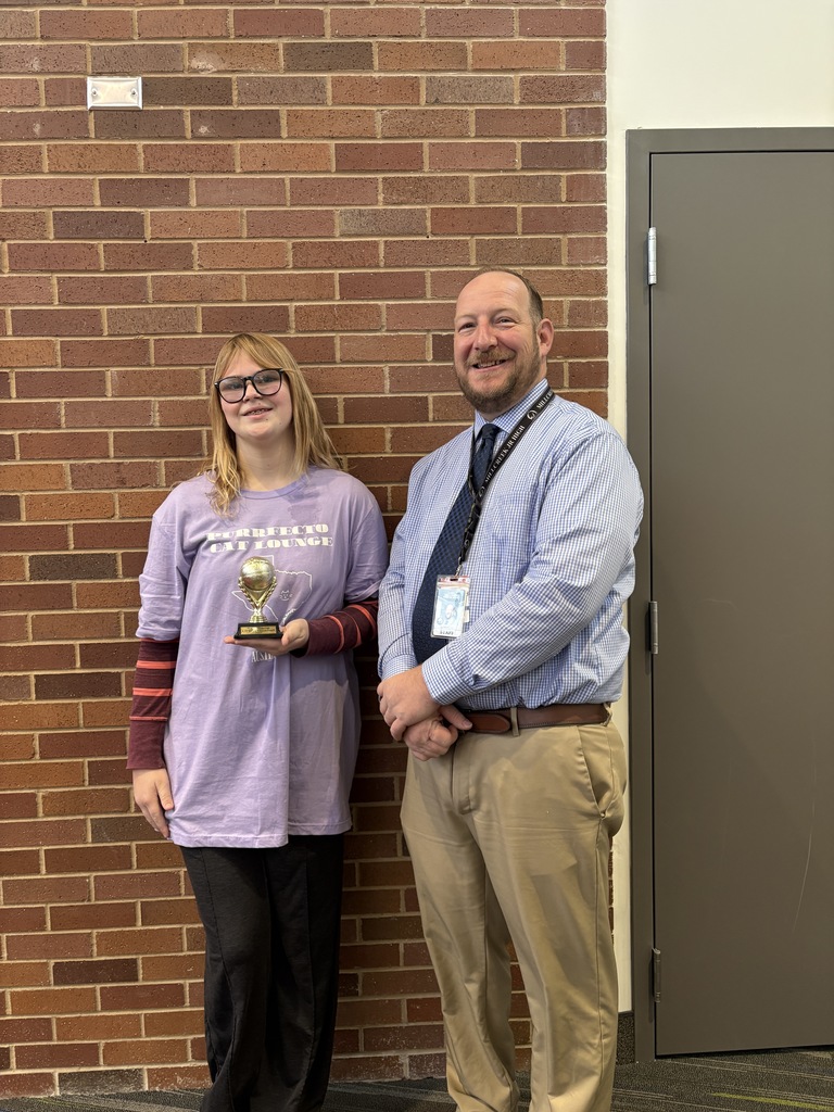 an image of a student holding a trophy from her competition. She is standing beside Principal Hansen