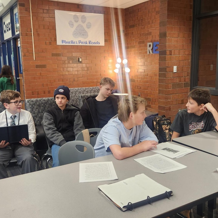 A group of students sitting in a table with papers on the desk at a mock trial event