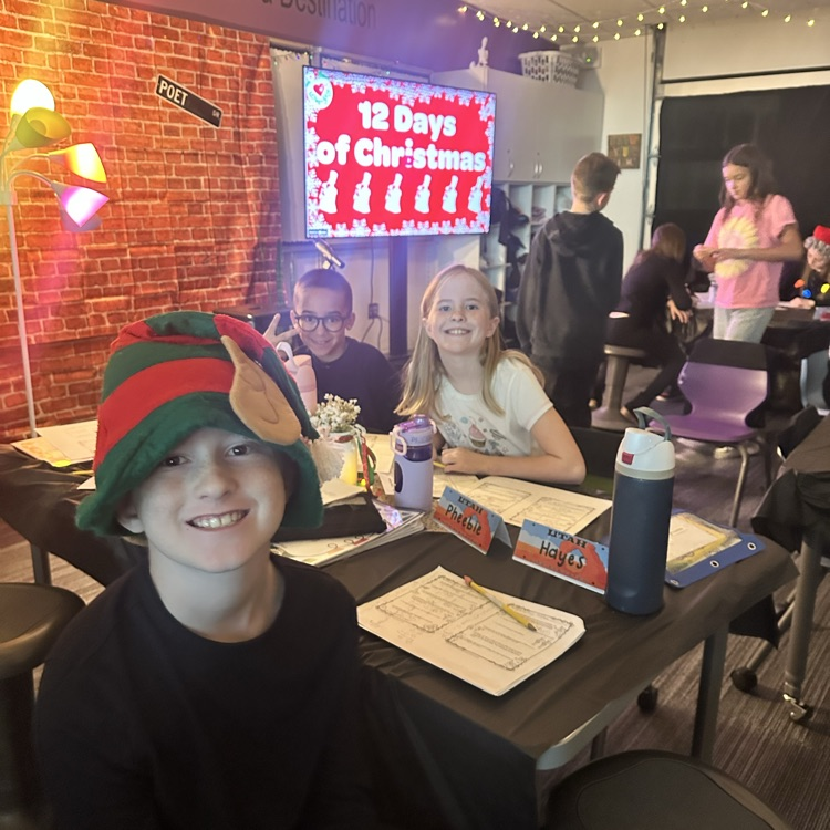 boy and girl smiling at camera with 12 days of Christmas behind them