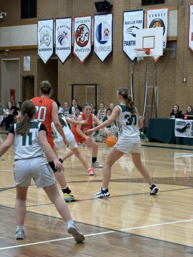 image of a girl playing basketball being blocked by other players