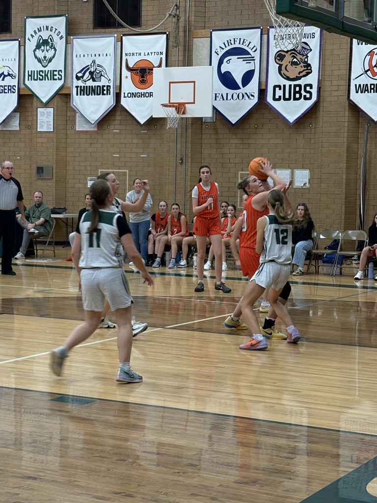 image of girl basketball player shooting the ball at the basket with other players around her