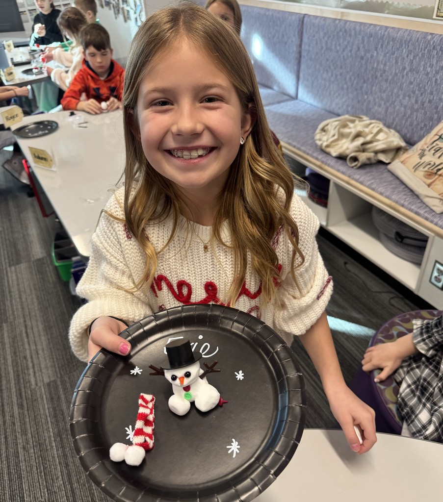 girl smiling while holding black plate and snowman on it