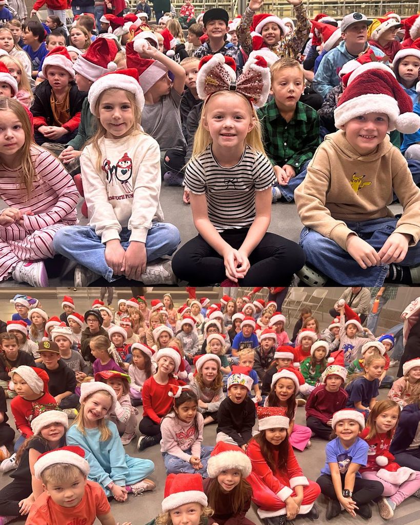 Elementary students wearing Santa hats sit cross legged on the gym floor during a holiday sing along assembly. Several students smile toward the camera while others watch the performance.