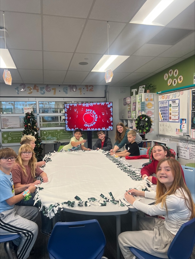 a group of students around a table with a blanket tying the ends