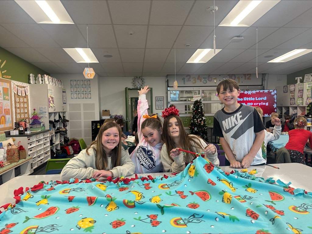 students tying a blanket while smiling