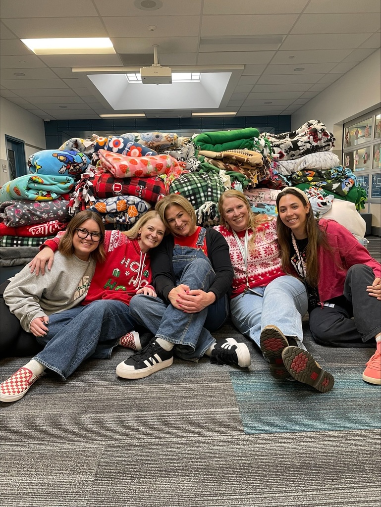 5 women smiling in front of a pile of blankets