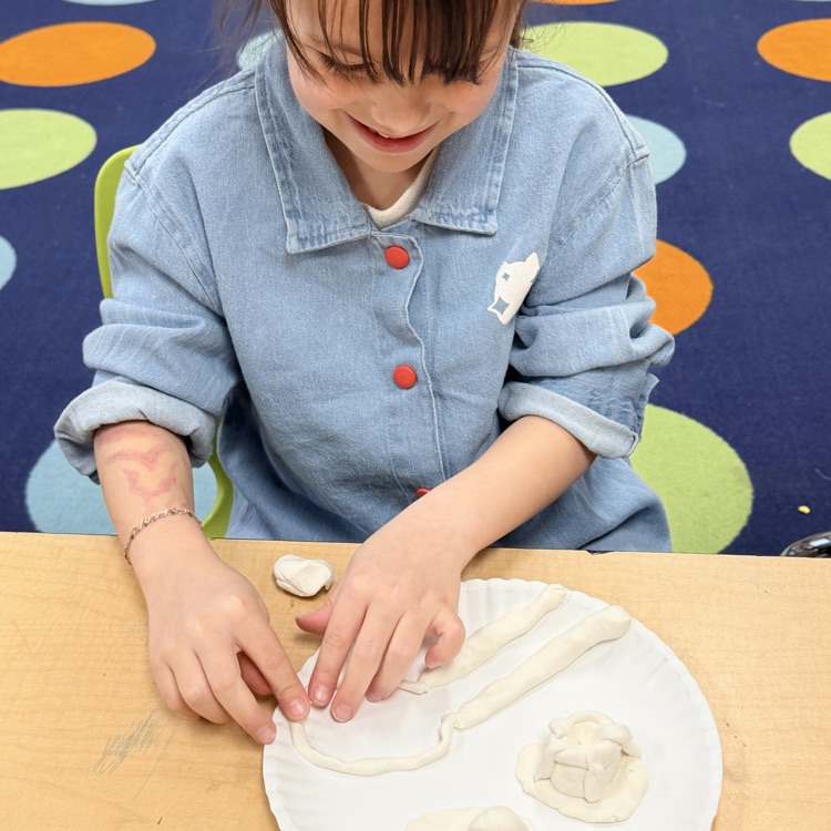 second grader using clay to create a model of landforms and bodies of water