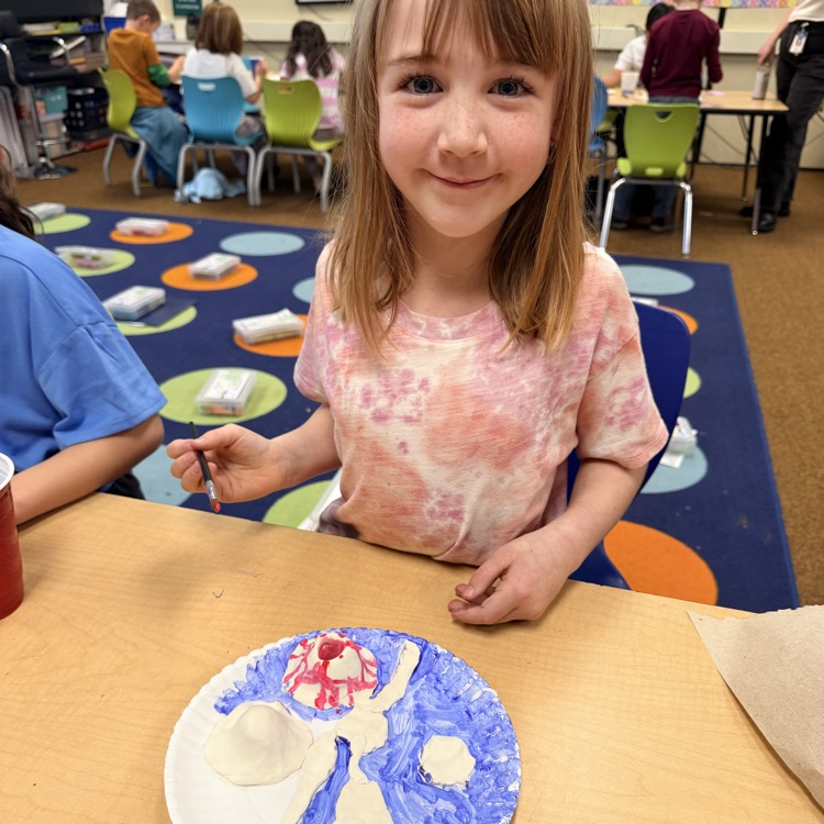 second grader painting their clay model of landforms and bodies of water