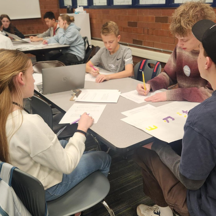 students sitting at a table writing on papers