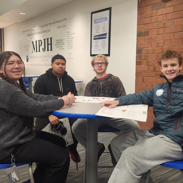 students sitting around a table smiling at the camera