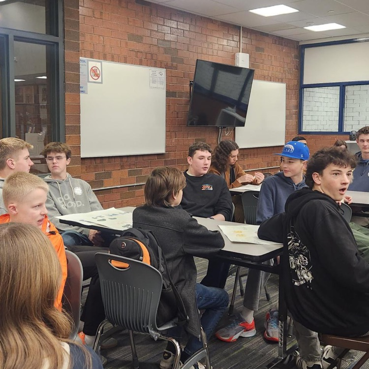  group of students sitting at a table learning from a chinese project