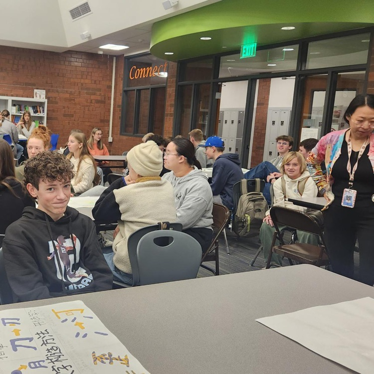 a group of students sitting around a table learning from a chinese project