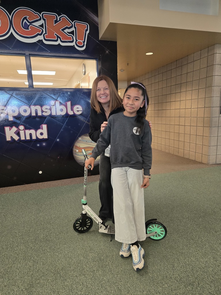 second term scooter winner standing with principal and new scooter