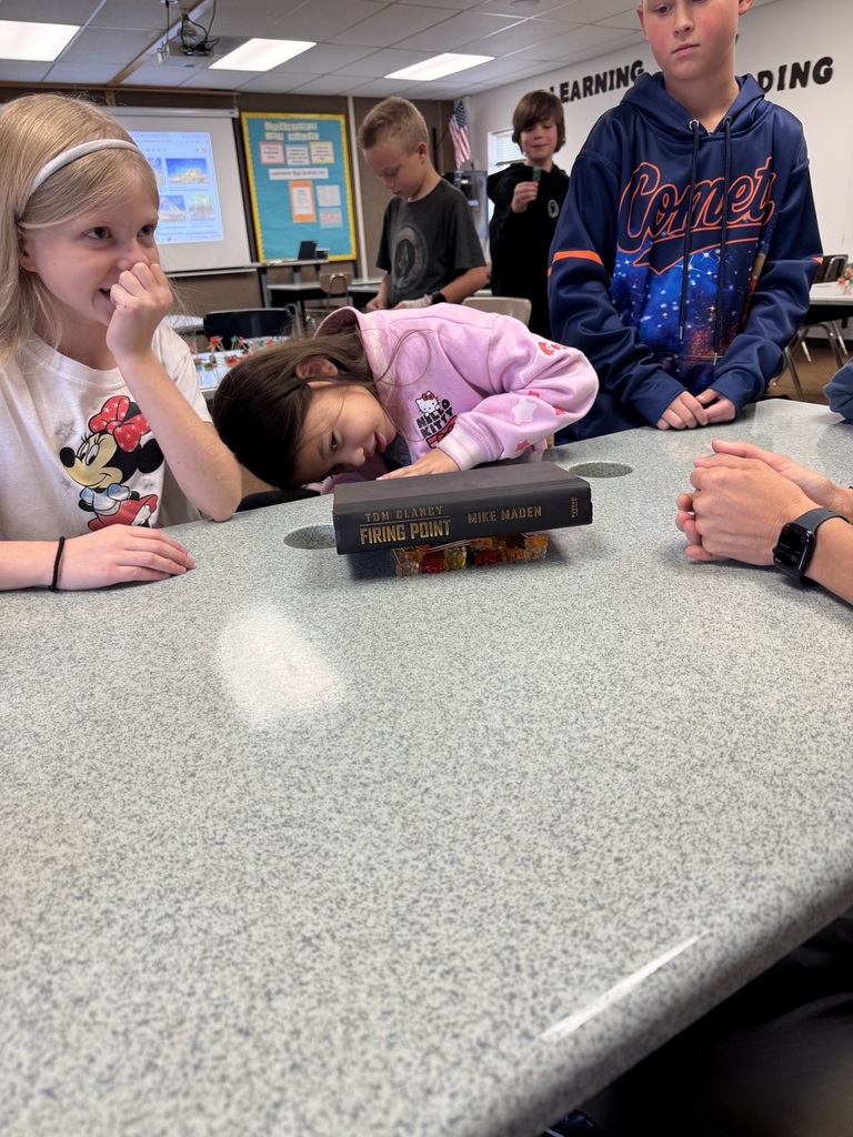 Kids testing the strength of a structure by placing a book on top of it.