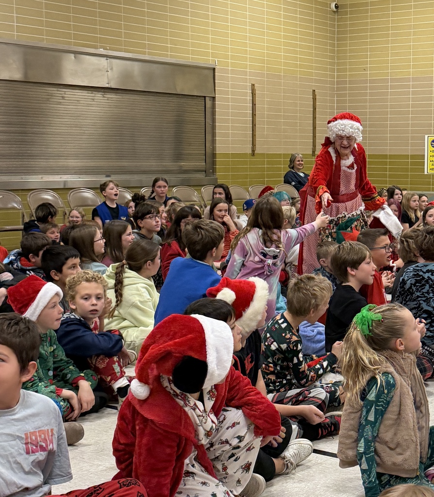 Mrs. Claus handing out candy canes to kids during a christmas assembly