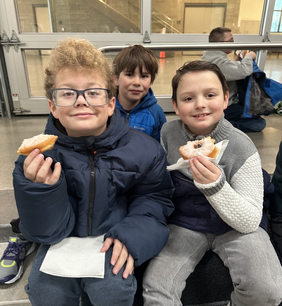 3 boys sitting down eating donuts