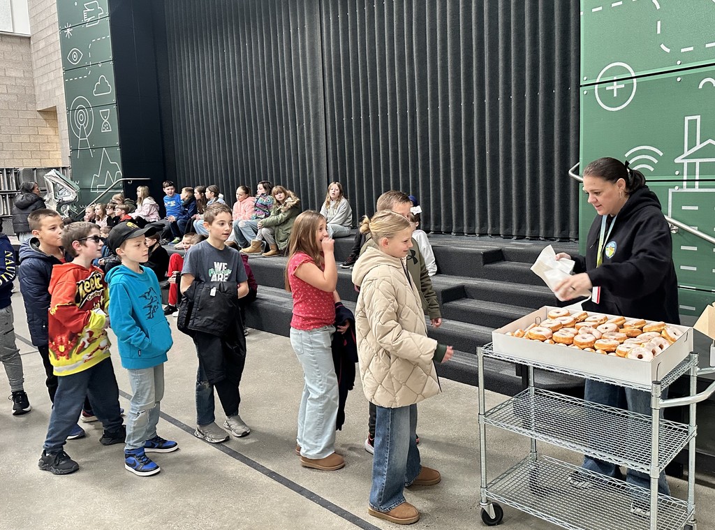 women passes out donuts to students in line