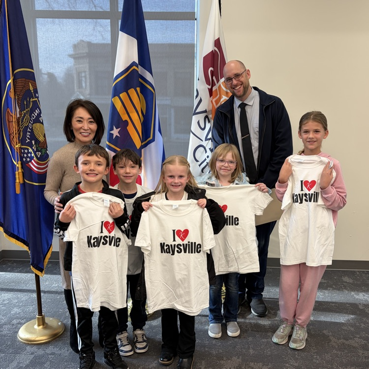 Our students, Principal and Mayor Tran are shown standing in front of a United States Flag, Utah state flag, and a Kaysville flag. 