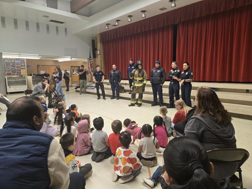 a group of preschool students sit in a gym, watching and listening to the Bountiful Fire Department talk about fire safety!