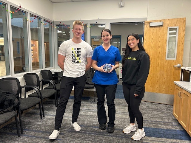 2 members of Alloy Personal Training presenting a donation to the kitchen manager.