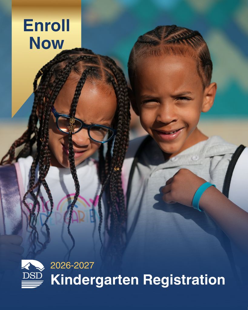 Two young children smiling outdoors, standing side by side. A banner in the corner reads “Enroll Now.” Text at the bottom says “DSD 2026–2027 Kindergarten Registration” with the district logo.