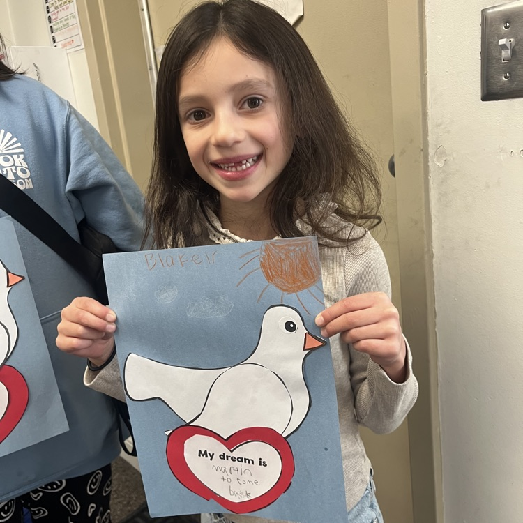 girl smiling with white shirt holding a blue paper with dove on it