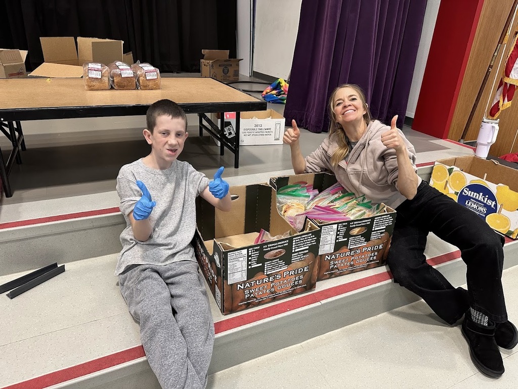Students and teacher posing while packaging sandwiches.