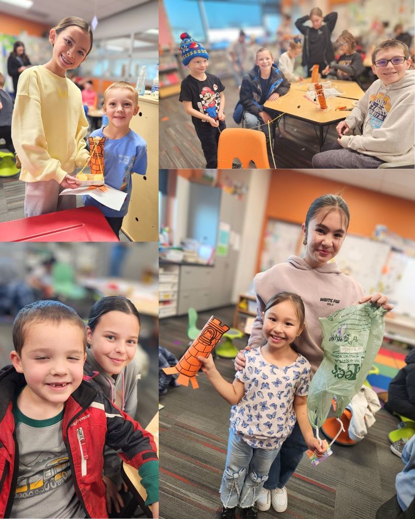 Pairs and small groups of 6th grade buddies posing with kindergarten students beside their paper tower projects during buddy time in the classroom.