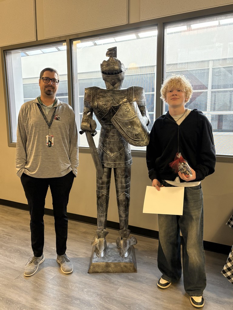 image of a student and teacher standing next to a knight statue.