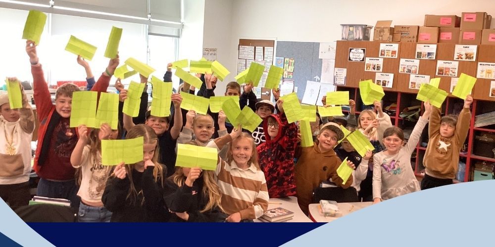 Students posing with a folded piece of paper.