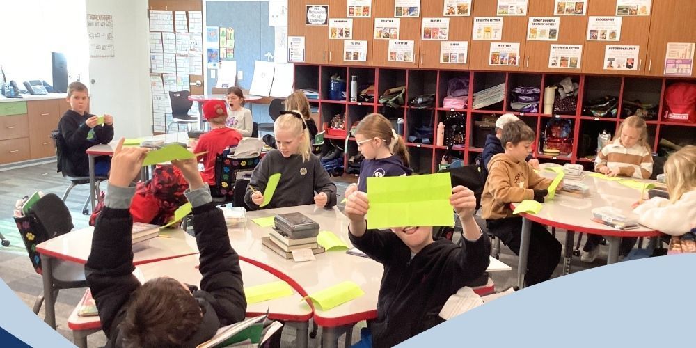 Student posing for a picture with their folded piece of paper.