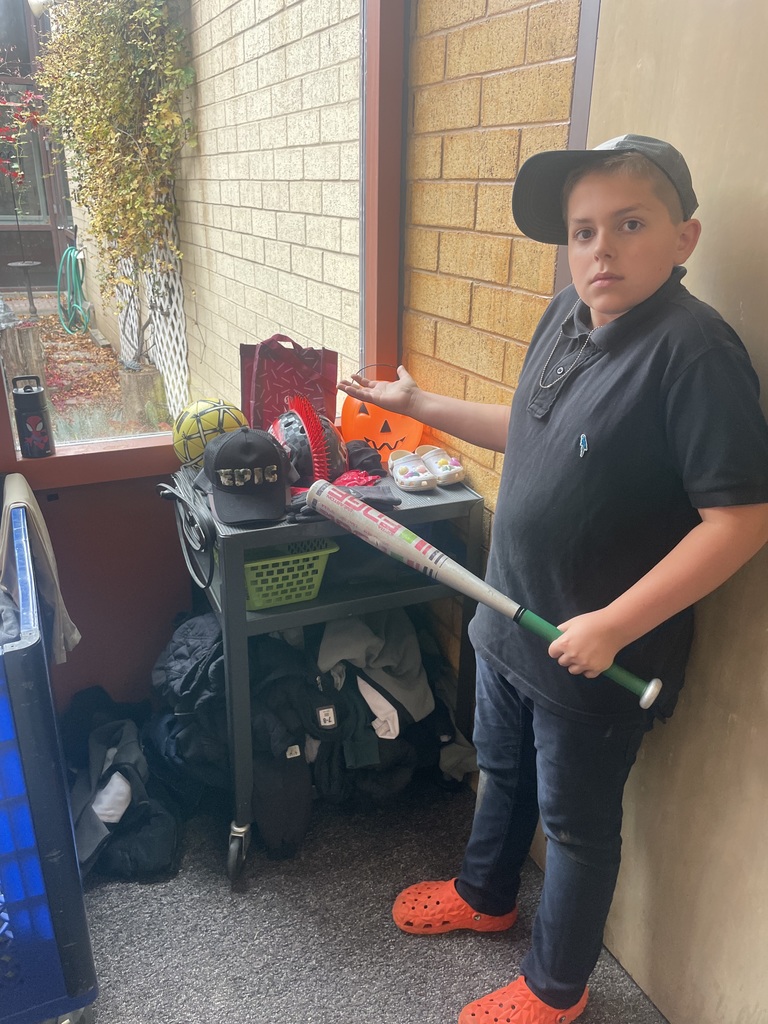 students standing next to the lost and found bucket holding out his hand to show how much is in there