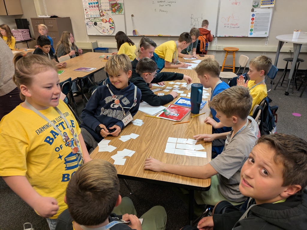 a large group of students at a large table participating in book battle activities