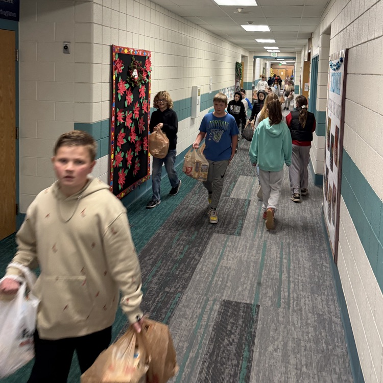 Students are shown carrying bags and boxes of donations into the school to be sorted.