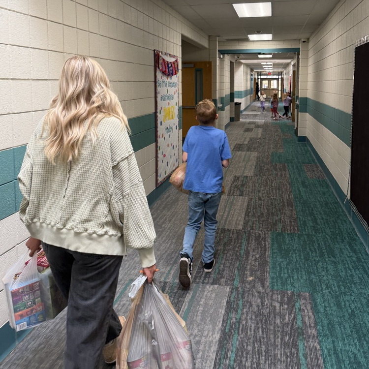Students are shown carrying bags and boxes of donations into the school to be sorted.