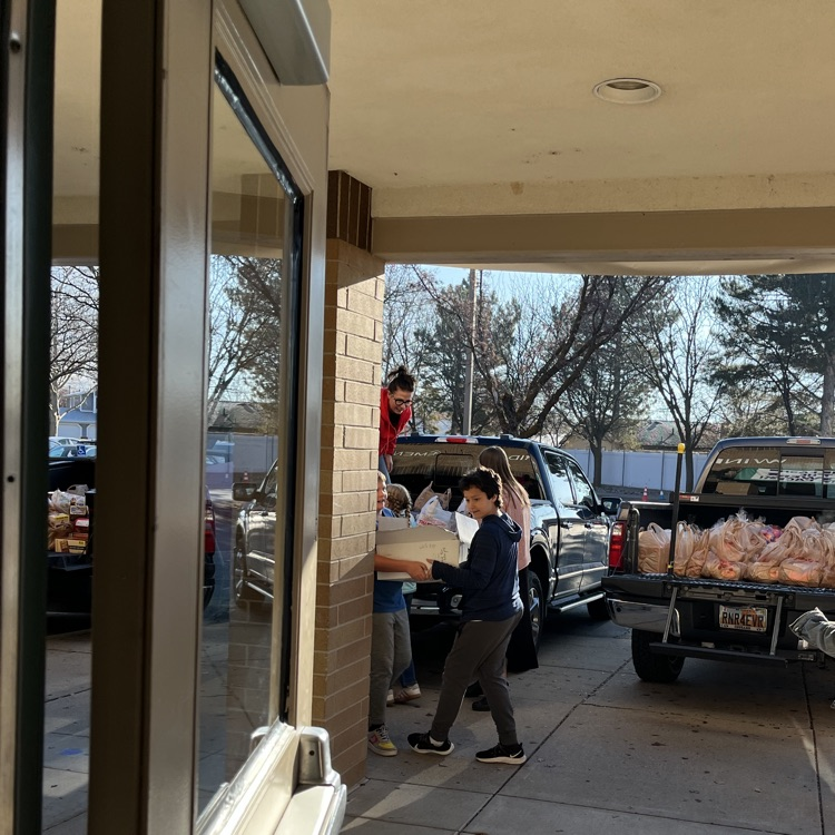Students are shown carrying bags and boxes of donations into the school to be sorted.
