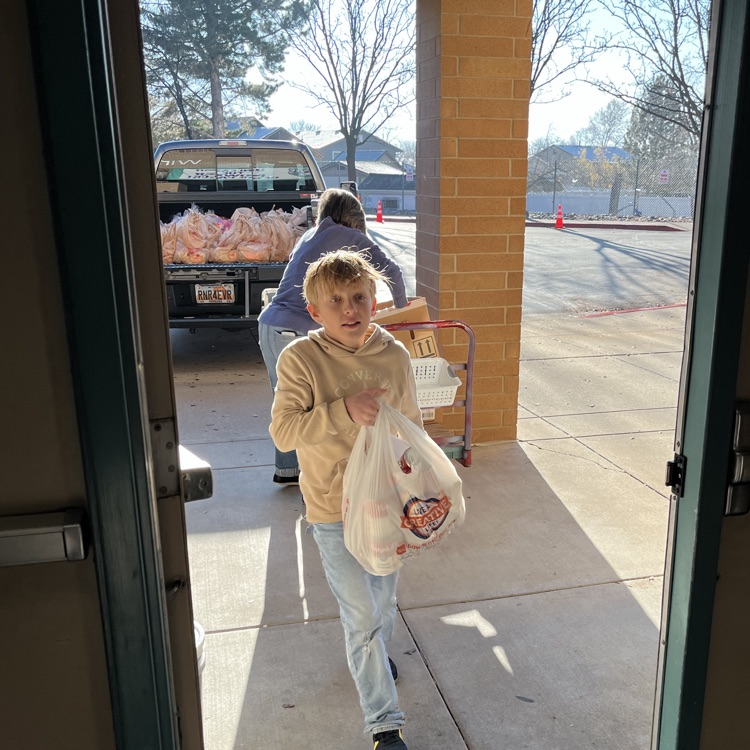 Students are shown carrying bags and boxes of donations into the school to be sorted.