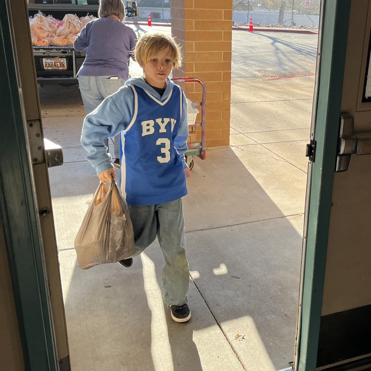 Students are shown carrying bags and boxes of donations into the school to be sorted.