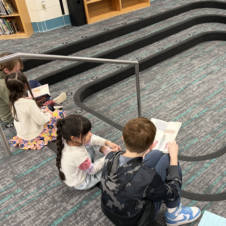Reading buddies! 6th graders and kindergarteners are shown reading together