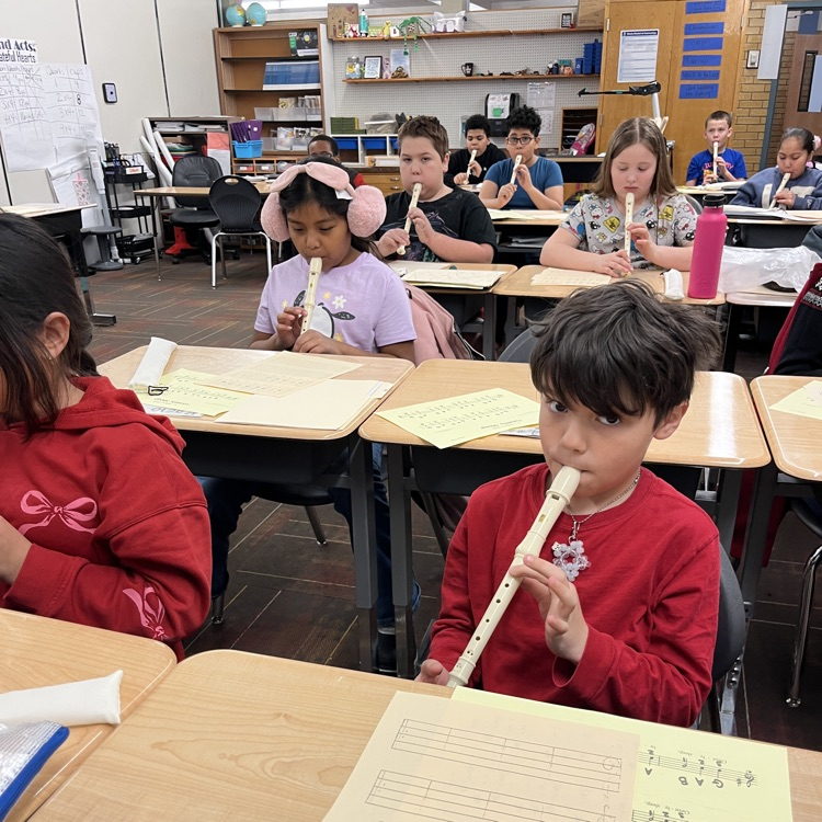 4th grade students in a classroom playing recorders